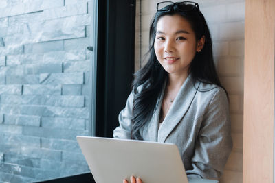 Portrait of young woman using laptop while sitting at home