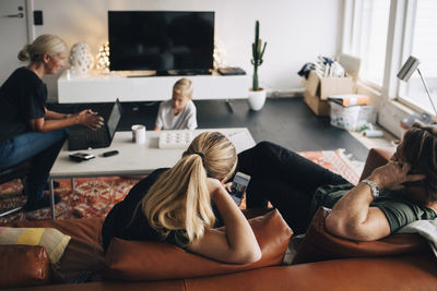 High angle view of family sitting in living room with technologies at home