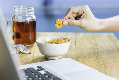 Cropped hand of woman using laptop on table