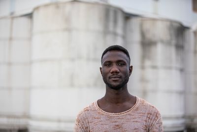 Portrait of young man standing against wall