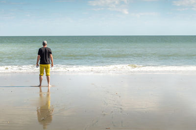 Rear view full length of man standing on shore at beach