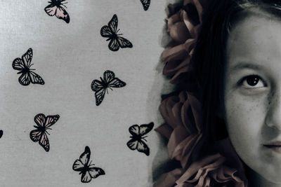Close-up of girl with butterflies painted on wall