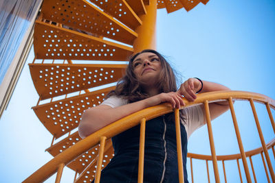 Low angle view of woman looking away while sitting on chair