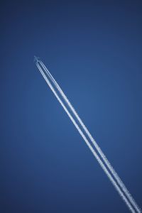 Low angle view of vapor trail against blue sky