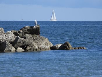 Sailboat on rock by sea against sky