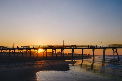 Silhouette pier over sea against clear sky during sunset