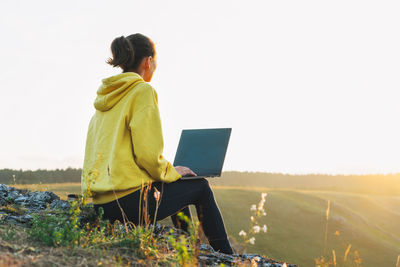 Woman using laptop on field