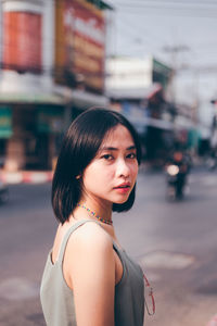 Portrait of young woman standing on road in city