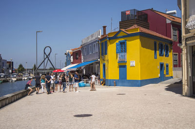 People on beach by buildings against clear sky