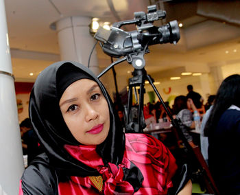 Portrait of woman sitting by camera on tripod