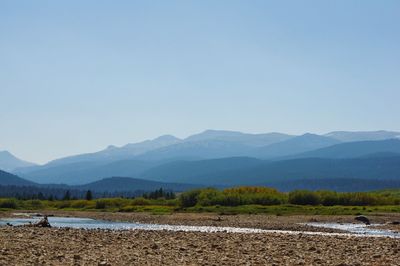 Scenic view of lake and mountains against clear blue sky