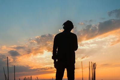 Rear view of silhouette man standing against sky during sunset