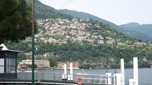 Scenic view of river by buildings and mountains against sky