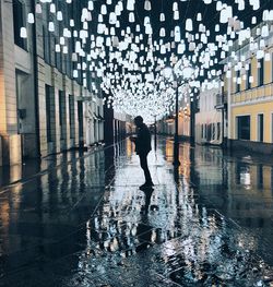 Full length of man walking on wet city street during rainy season