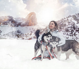 The girl rides on a sled on a sled with siberian huskies in the winter forest. 