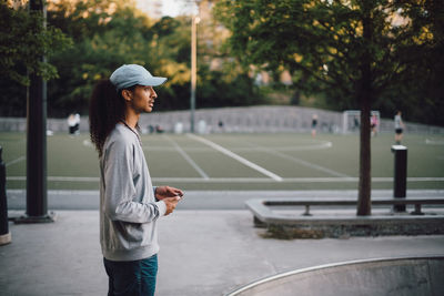 Side view of thoughtful man standing at skateboard park