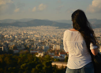 Rear view of young woman with cityscape in background