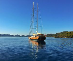 Sailboat sailing on sea against clear blue sky