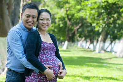 Portrait of man with pregnant wife standing on field