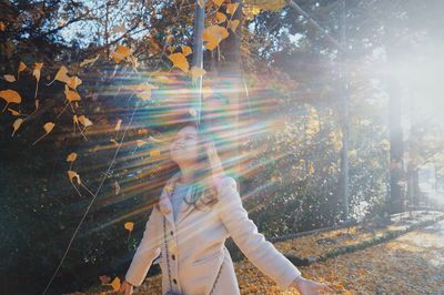 View of person walking through autumn leaves in forest