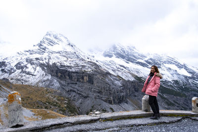 Woman standing on snowcapped mountain against sky