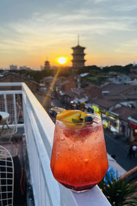 Close-up of beer glass against orange sky