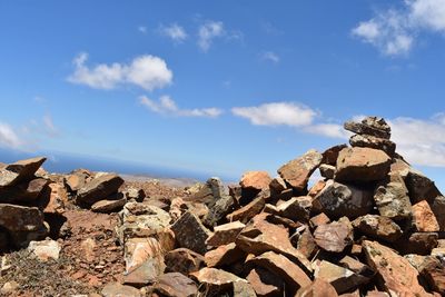 Stack of rocks on mountain against blue sky