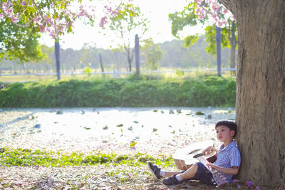 Boy playing guitar while sitting in park