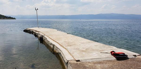 Rear view of man sitting on sea against sky