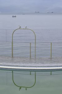 Swimming pool by sea against sky