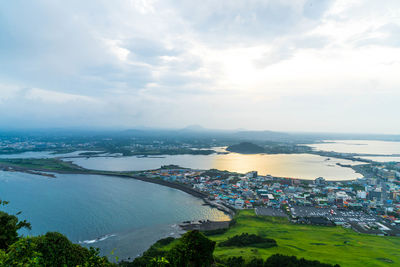 Townscape by sea against cloudy sky