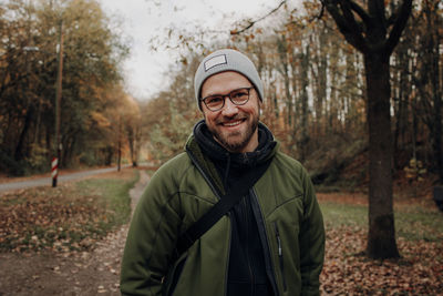 Portrait of smiling young man standing in fall environment 