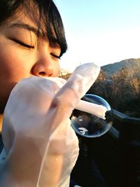 Close-up of hands against water against clear sky