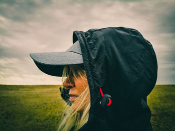 Woman with umbrella standing on field against sky