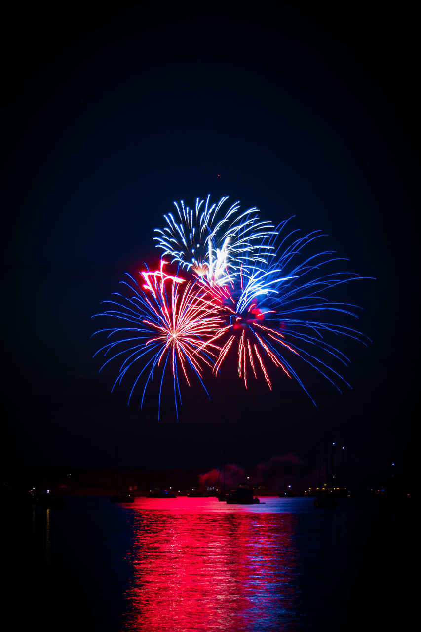 FIREWORK DISPLAY OVER RIVER AGAINST SKY AT NIGHT
