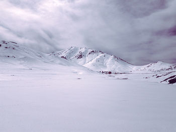 Scenic view of snowcapped landscape and mountains against cloudy sky 