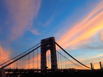 Low angle view of suspension bridge against cloudy sky