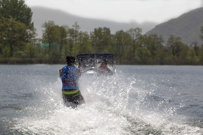 Rear view of man wakesurfing in river