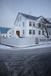 Snow covered houses by buildings against sky