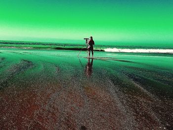 Man walking on beach against clear sky