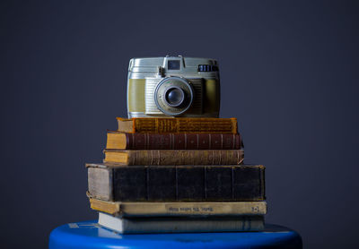 Close-up of old-fashioned camera on old books against black background