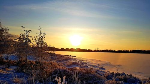 Scenic view of snow covered land against sky during sunset