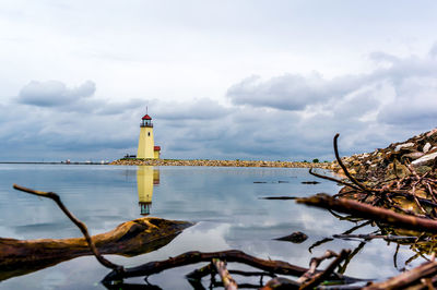 Lighthouse reflecting on lake hefner against cloudy sky