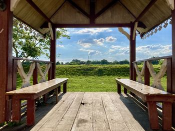 Empty bench on table by trees against sky