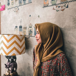 Smiling woman looking away while standing against wall