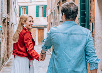 Couple holding hands while standing against buildings