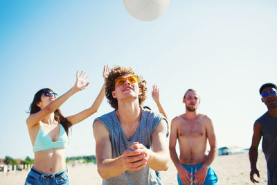 Group of people at beach against clear sky