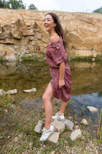 Full length of woman standing on rock by the lake 