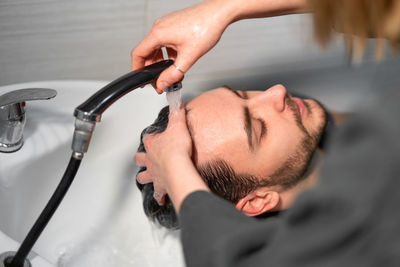 High angle view of barber washing customer hair in salon