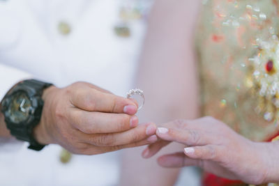 Close-up of bridegroom inserting wedding ring in bride finger